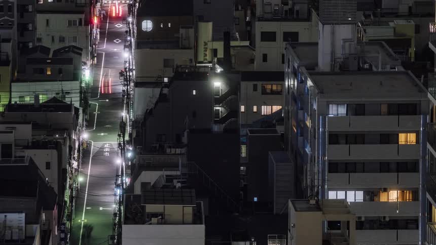 Traffic and pedestrians travel along a street in an urban area at night