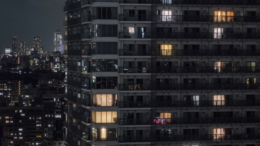 The lights in apartments in a high rise building are turning off at night