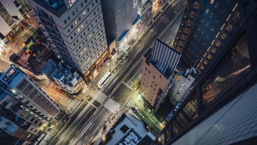 Traffic and pedestrians travel along a street in an urban area during the night