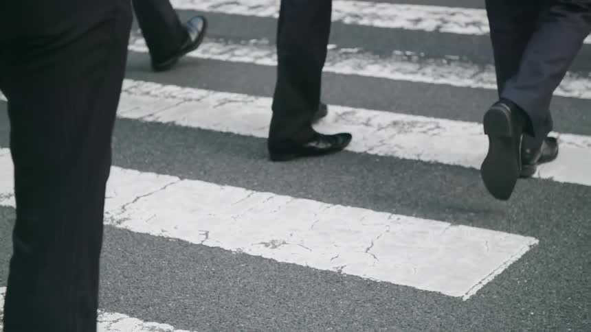 Pedestrians cross a city street crosswalk