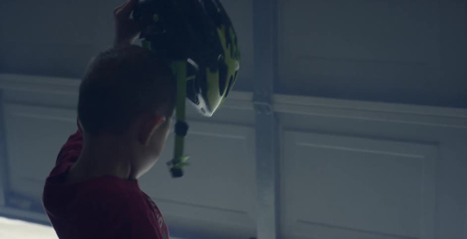 A young boy puts on a bicycle helmet