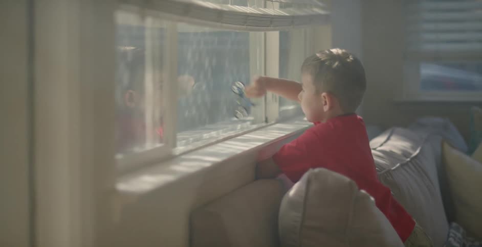 Boy playing with a small bicycle figure on a window and its pane