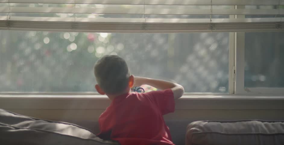 A boy rolls a toy bicycle on a window sill