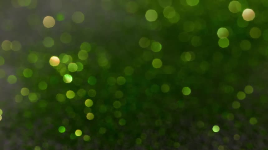 Green glitter is refracted by light and creates a shiny bokeh