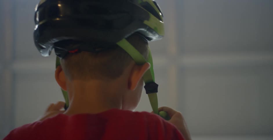 A boy puts on his bicycle helmet