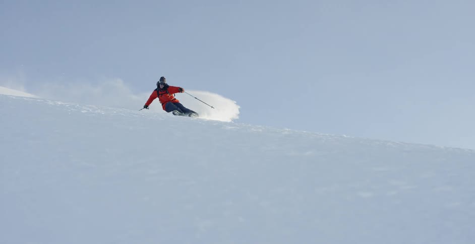 A person skis down the slope turning fast in the snow