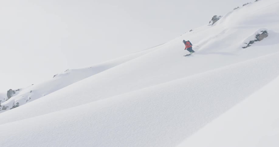 A skier is skiing down a mountain slope during the day