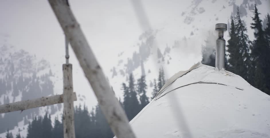 Smoke pours from a chimney on a snowy day