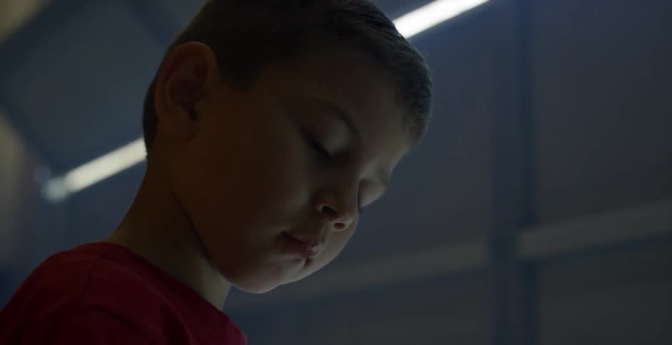 A young boy looks down in a garage