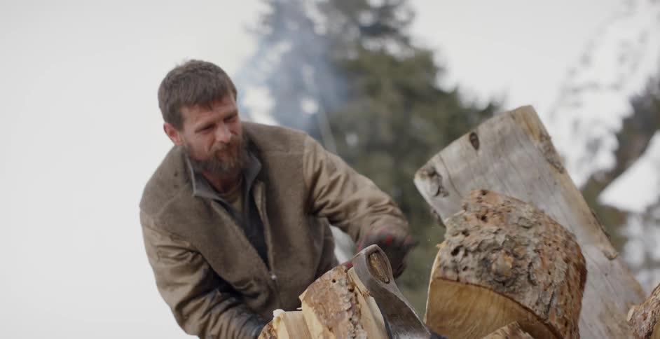 Man axes into a large stump of wood