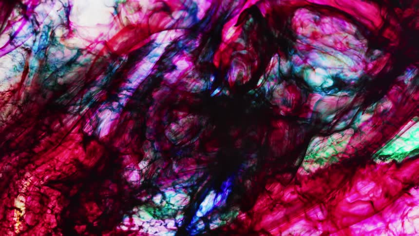 Different colors of liquid swirl together in a cloudy pattern