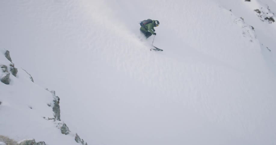 Person skis down a large snowy hill