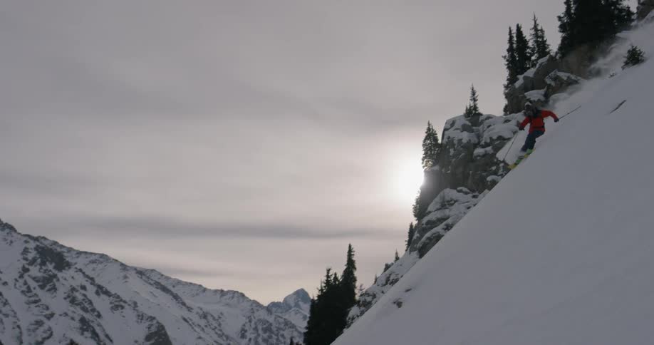 Person skis downhill on a snowy mountain
