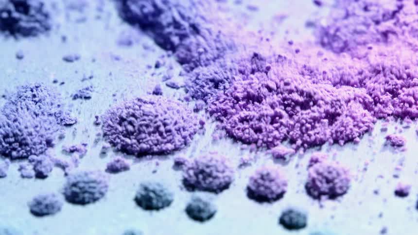Purple and blue powder vibrates and bounces on a plate