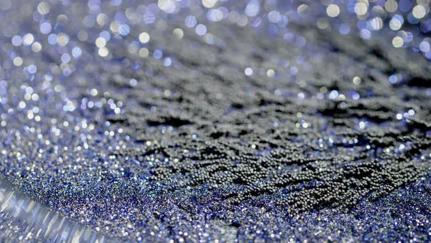Magnetic shavings move in unison surrounded by blue glitter