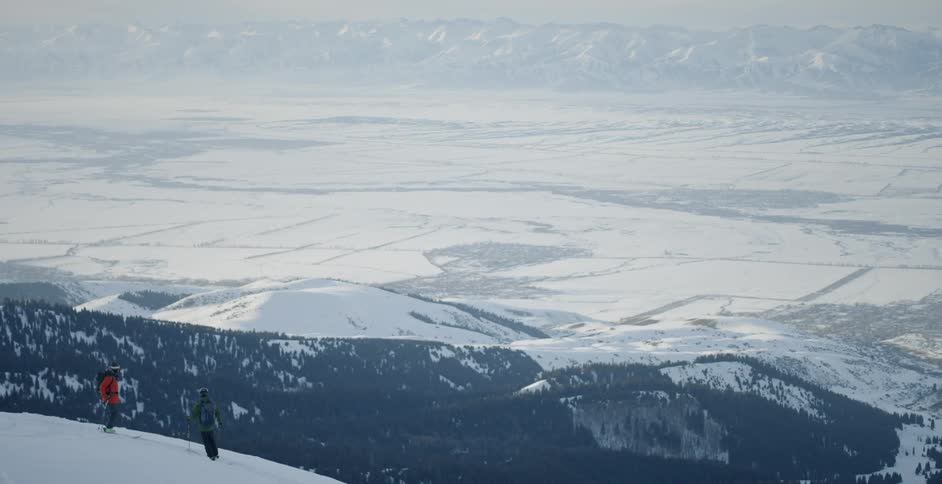 Two people stand on a snowy mountain on a sunny day