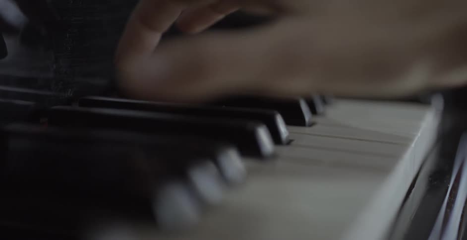 A hand plays a piano