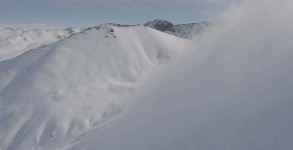 Powdery snow flying up as a skier skis by on a cloudy day