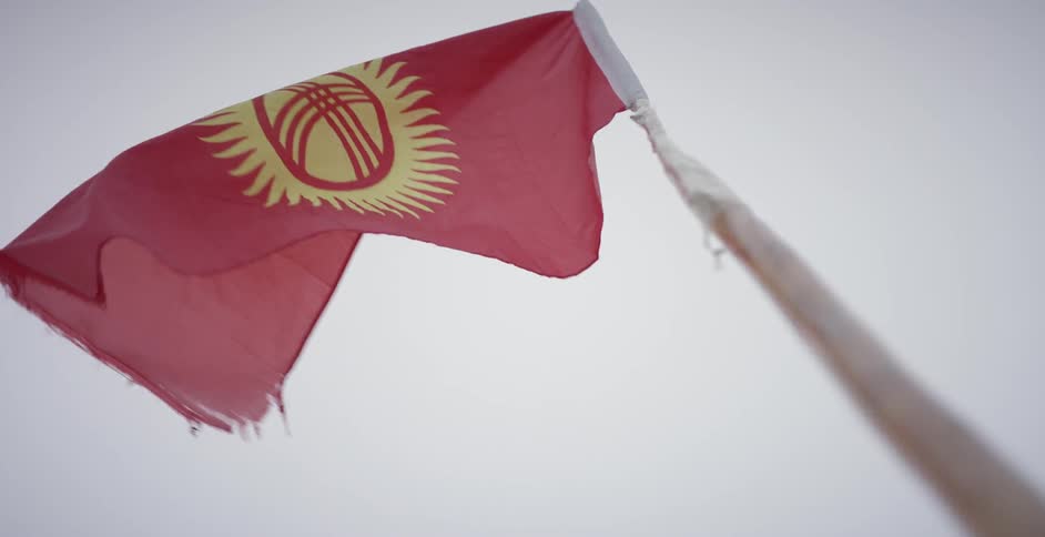 A kyrgyzstan flag is blowing in the breeze during the day