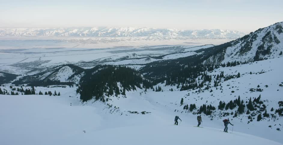 Skiers hiking up a hill with backpacks on