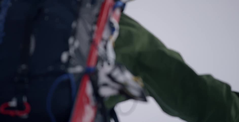 A skier climbs up with skis on his back