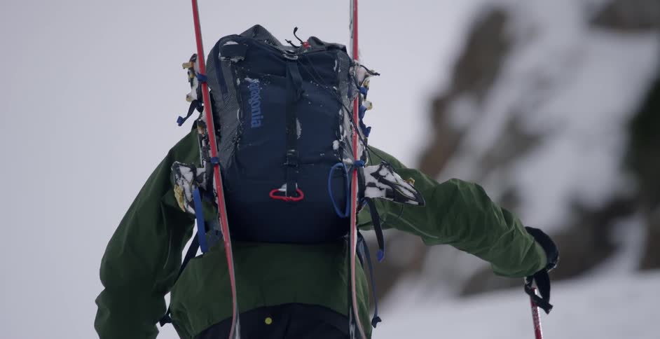 Man carrying his skiing equipment ascending a snowy slope