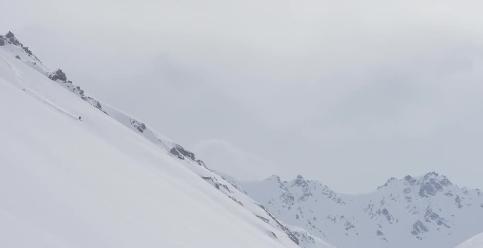 A skier is skiing down a mountain slope during the day