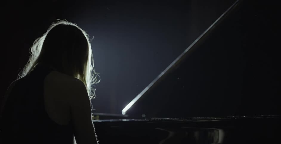 A woman is playing a piano inside on a stage