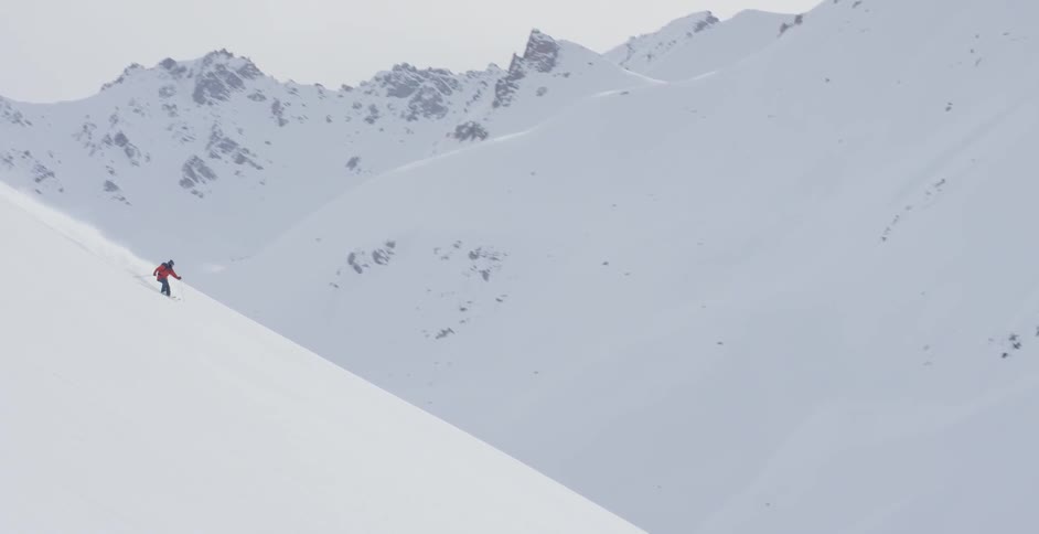 The person in a red coat glides down the slope on skis