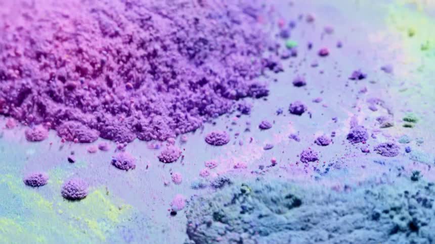 Brightly colored piles of particles bouncing quickly on a surface from its vibrations