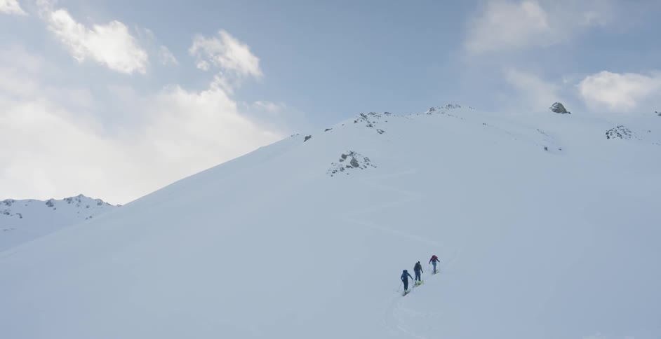 Three people climb up a snowy mountain