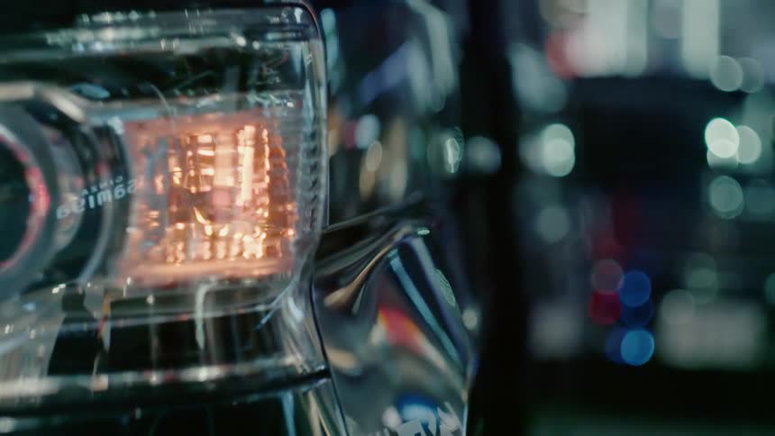 A light flashes and people and city lights are reflected on its surface