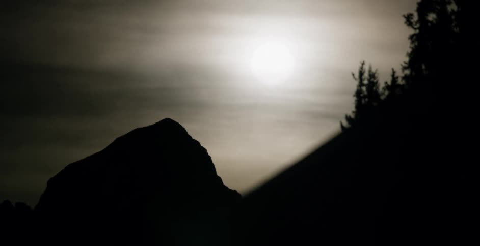 The clouds cover the sun above the mountains ahead