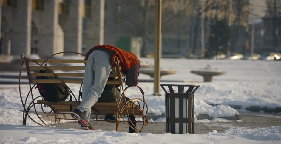 A person leans over a park bench