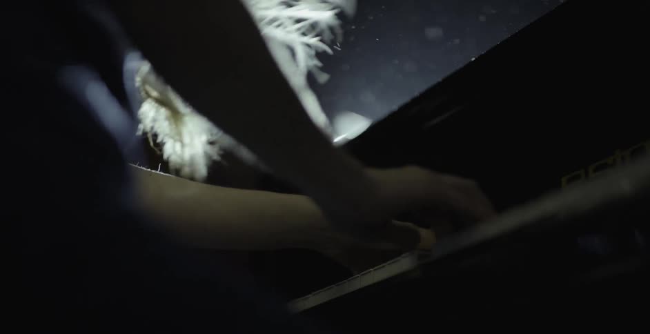 Person plays a piano illuminated by one light