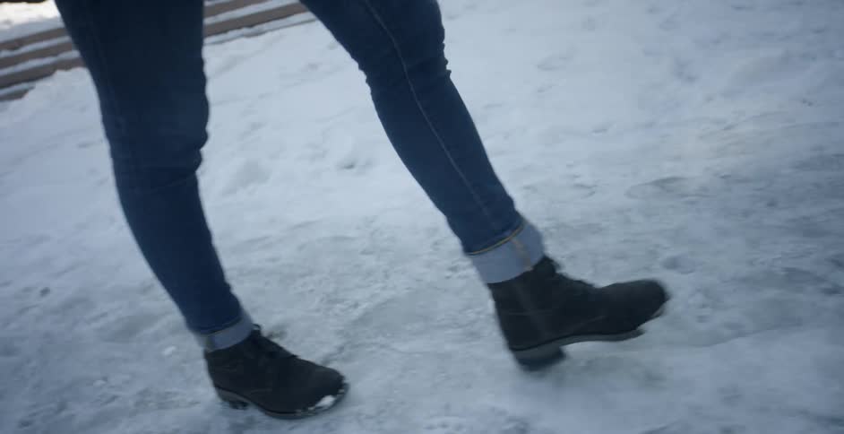A woman is walking on an icy street in daylight