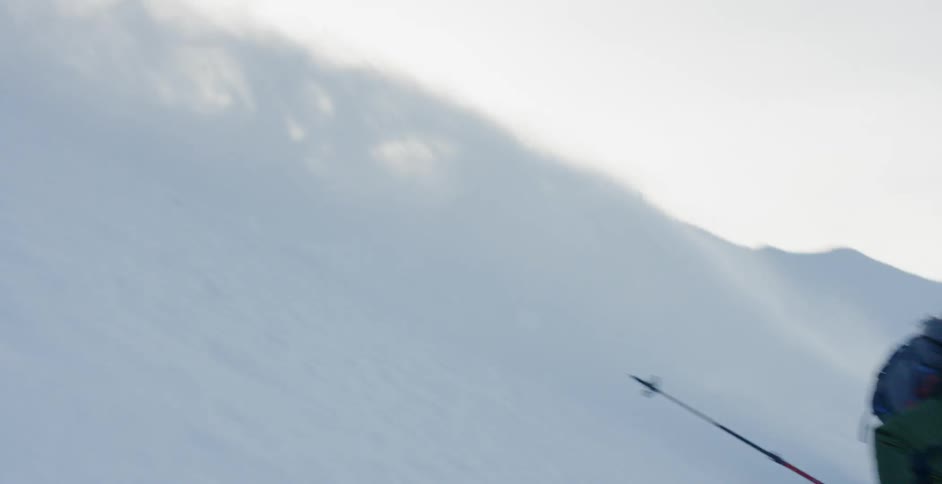 A person skis down a mountains slope on a sunny day