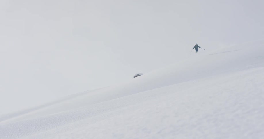 A person jumps and skis down a mountain slope