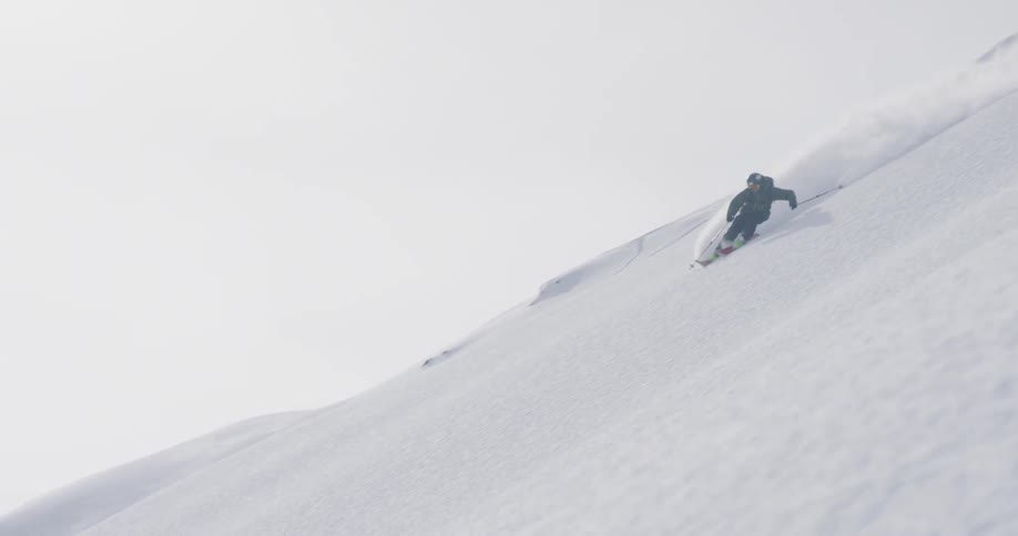 The skier turns gliding down the snow on a cloudy day