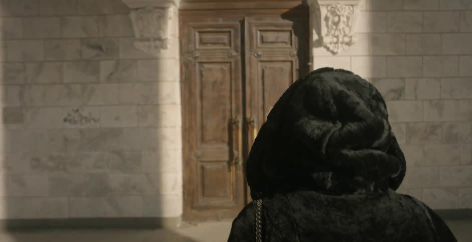A woman is approaching and entering a doorway in an old building during the day