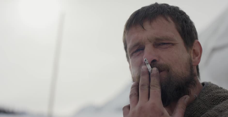 A man is smoking a cigarette on a cloudy day