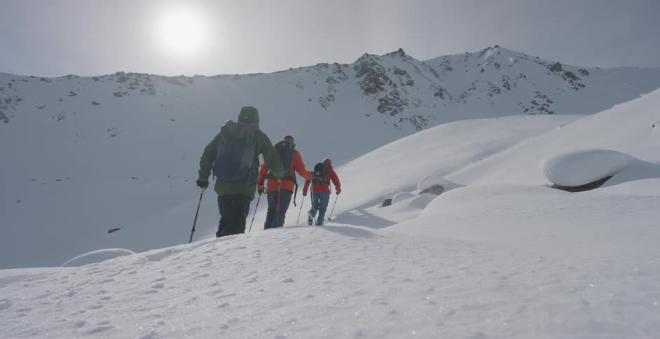 Three people hike up the snow filled slope