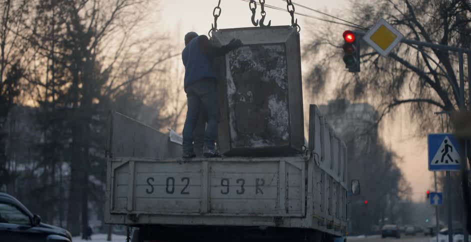 A worker places a container over a truck by the traffic light