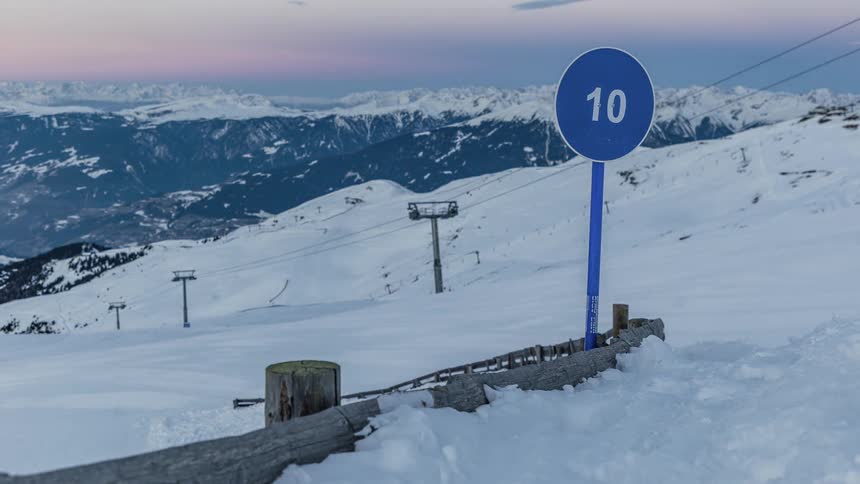 The sun is moving across the sky over a ski resort throughout a winter day