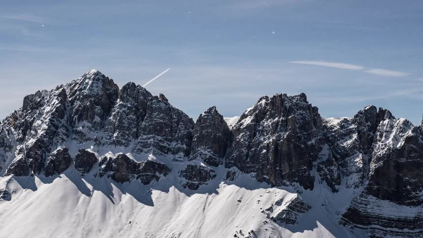 Jet leaves a trail as it flies above a snowy mountain