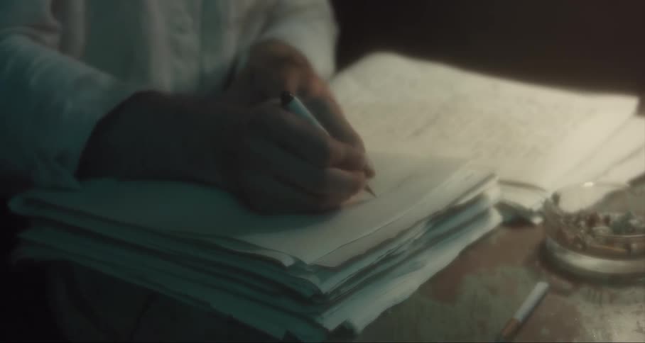 Man writes on paper at a desk with a pen