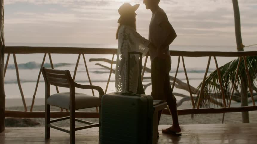 A man and woman are embracing on a porch at a beach at dusk