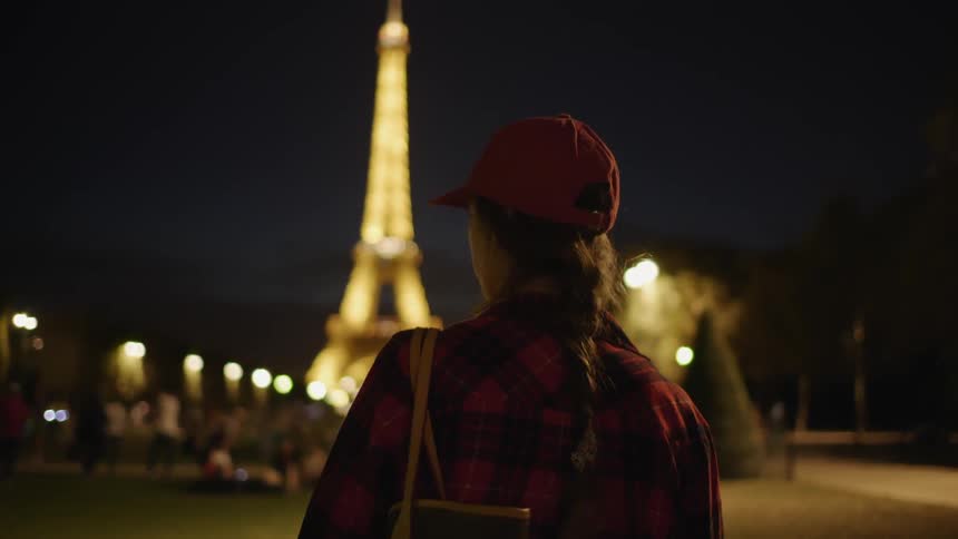 A woman walks towards the eiffel tower