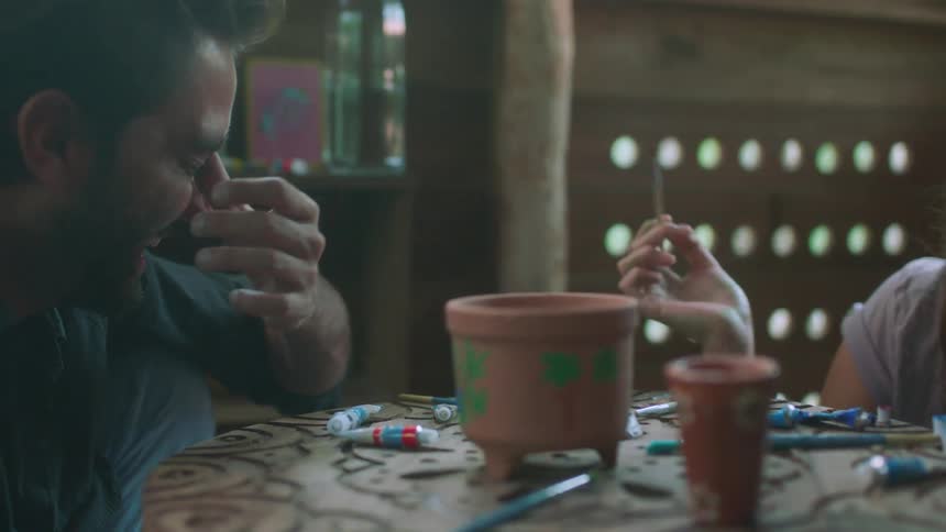 Man and woman laugh as they paint pottery
