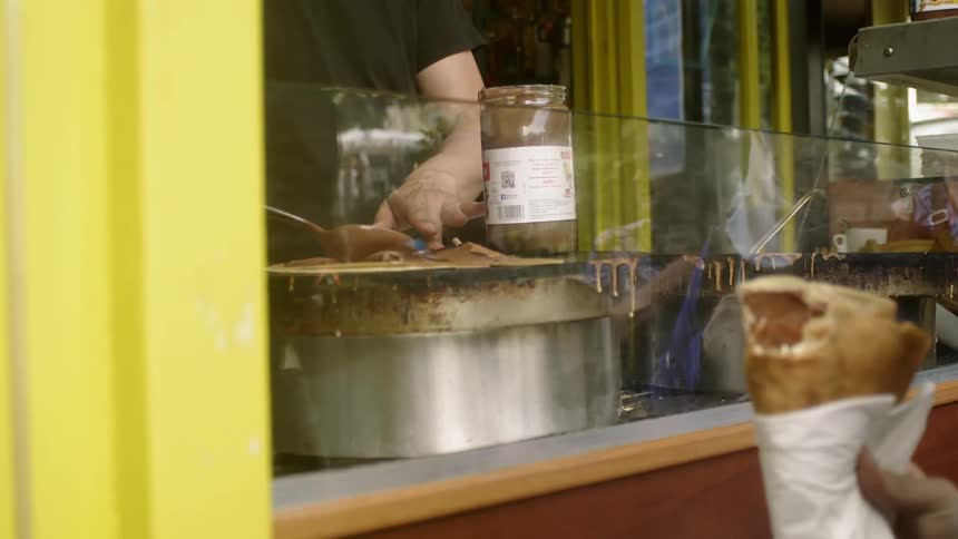 A man spreads a sauce onto a piece of food